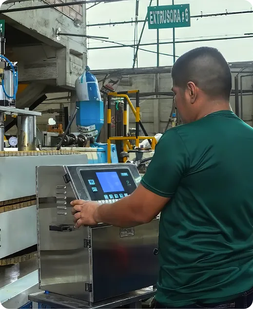 Operario supervisando maquinaria de extrusión en planta industrial